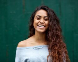 front-portrait-of-happy-young-Indian-woman-laughing-against-green-background
