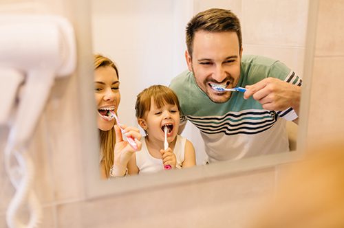 Happy-family-is-brushing-their-teeth-in-front-of-the-mirror-in-bathroom